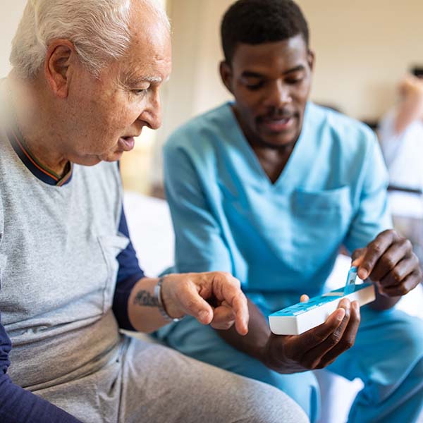 Healthcare worker helping elderly man with medications